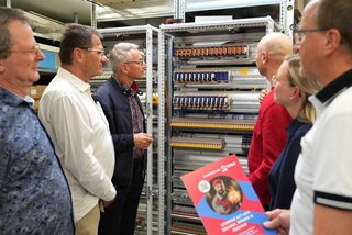 Der Angestellte Tilo Kulhavy (r. vorn) erklärt der Delegation einen im Aufbau befindlichen Schaltschrank am derzeitigen Produktionsstandort an der Chemnitzer Straße. Foto: Stadtverwaltung Flöha/ Erik Frank Hoffmann